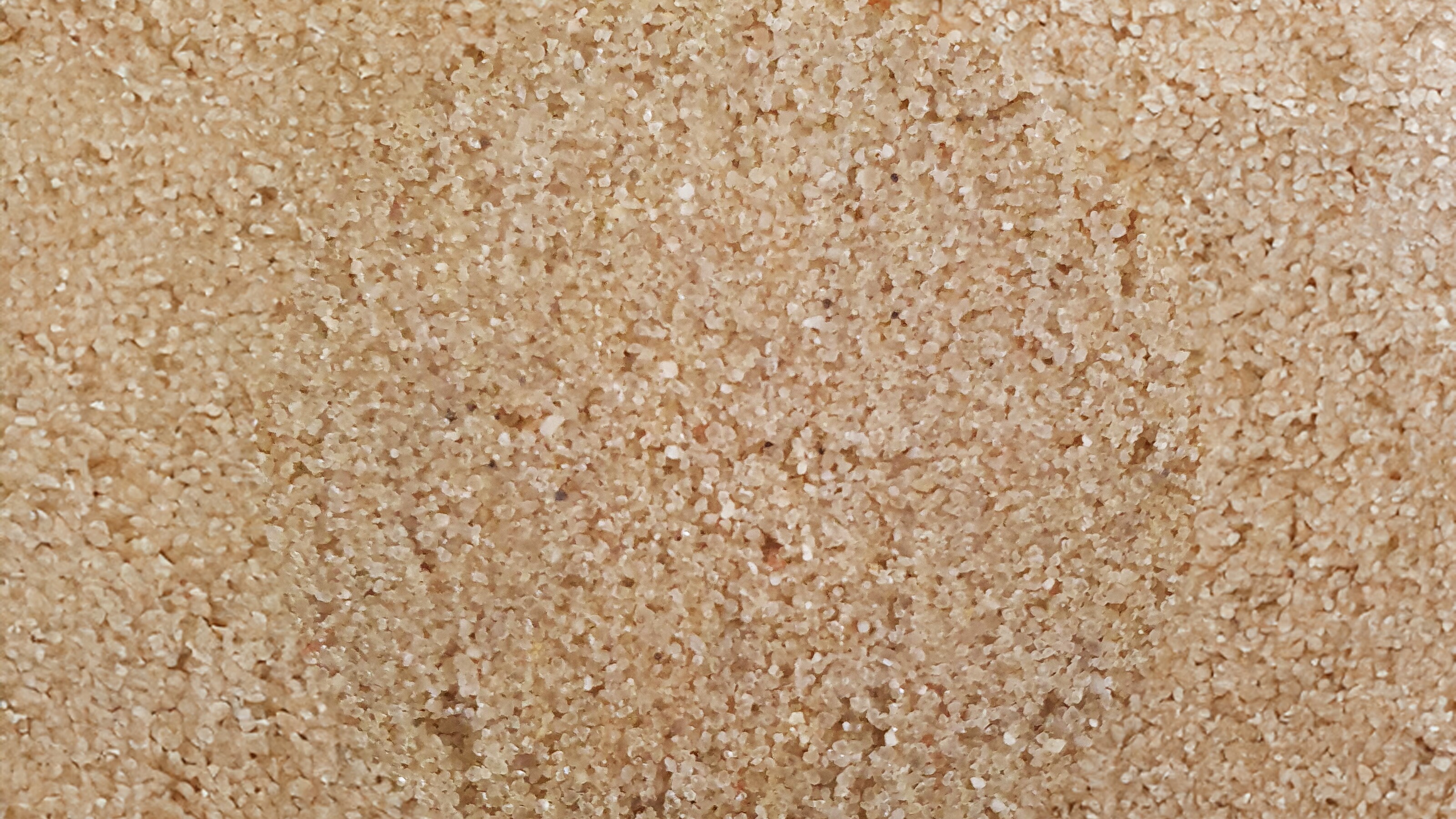 Close-up van ruwe beige steen- of betonnen textuur met kleine spikkels