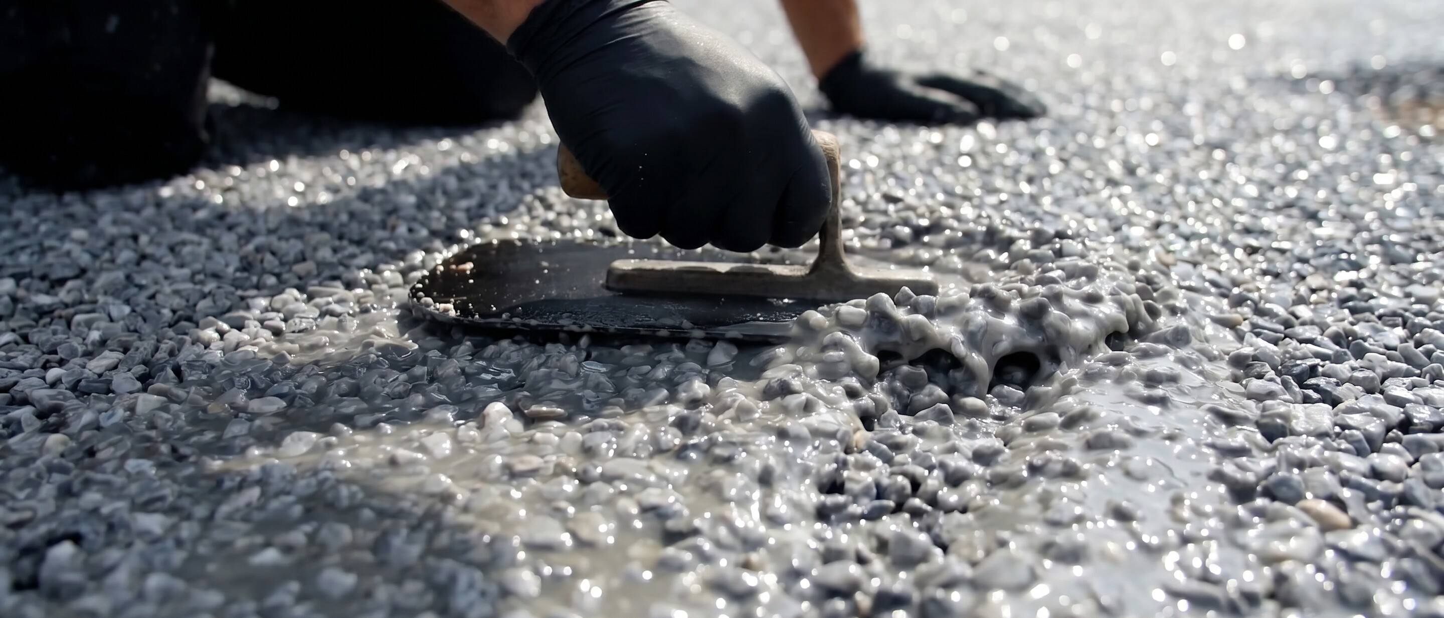 Des mains gantées étalant de l’asphalte sur une chaussée