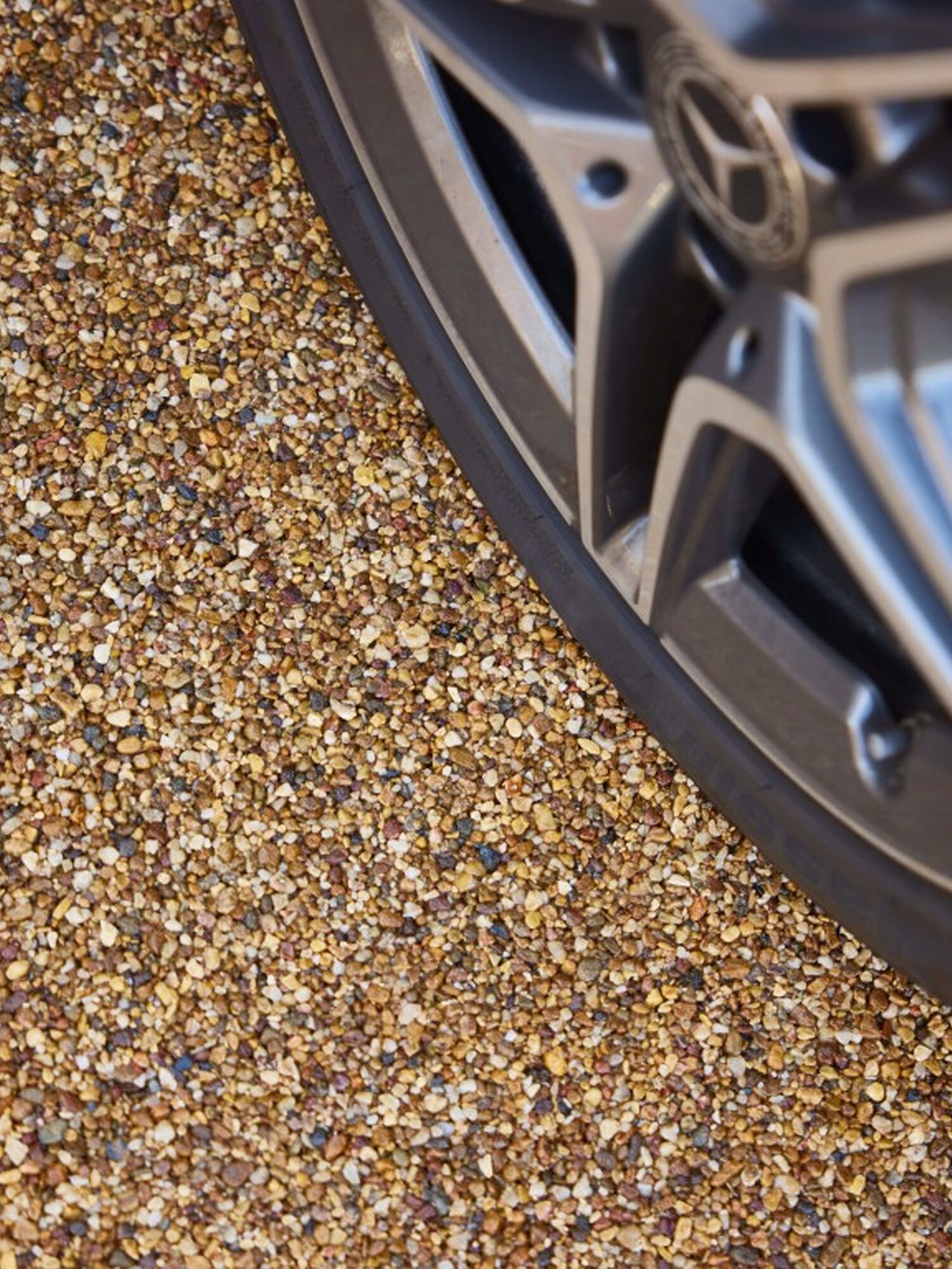 Close-up of a car’s alloy wheel on gravel
