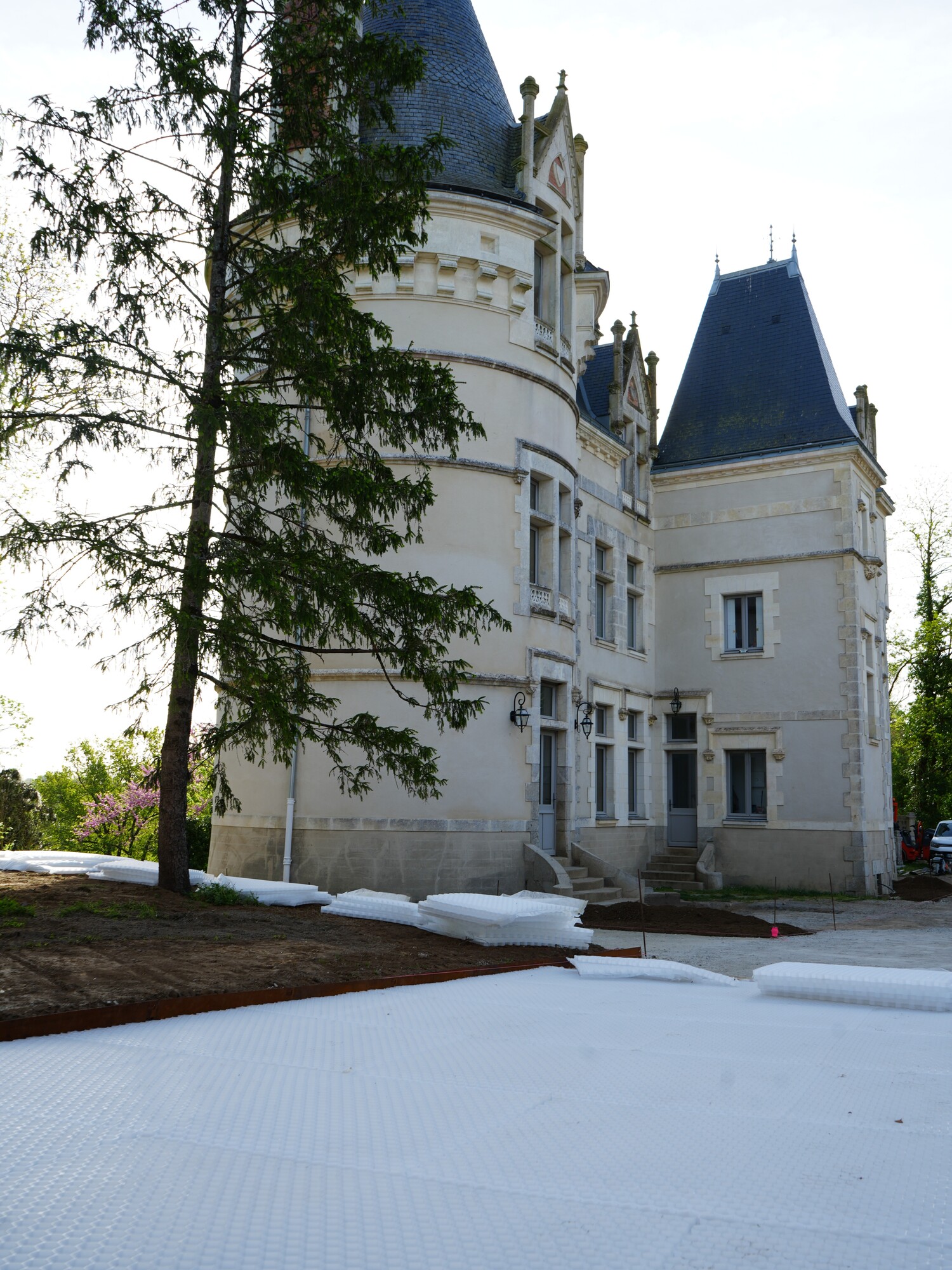 Bâtiment blanc semblable à un château avec des tourelles bleues derrière une pelouse enneigée