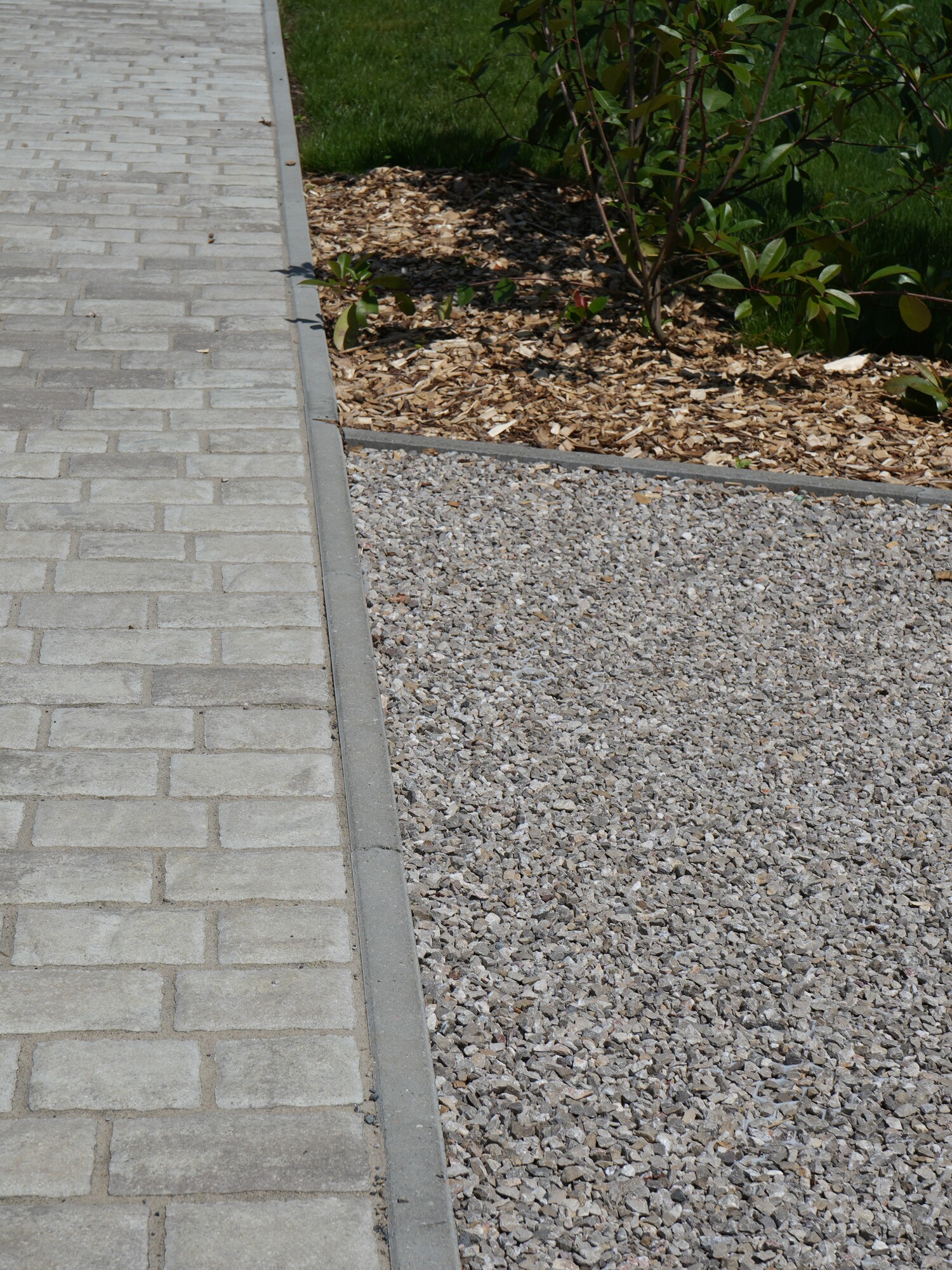 Paved sidewalk beside a gravel path near greenery