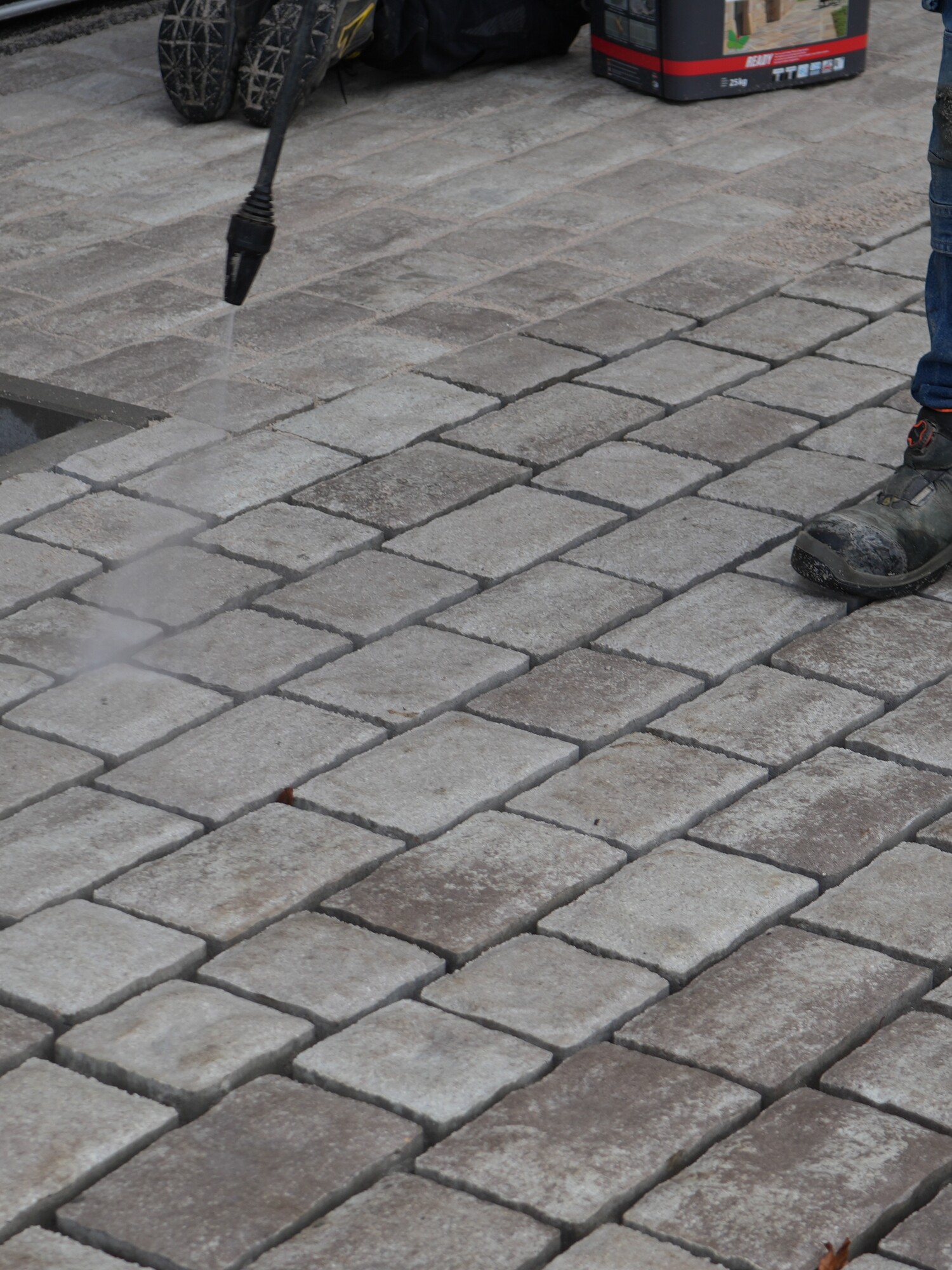 Worker standing on grey cobblestone pavement near a construction site
