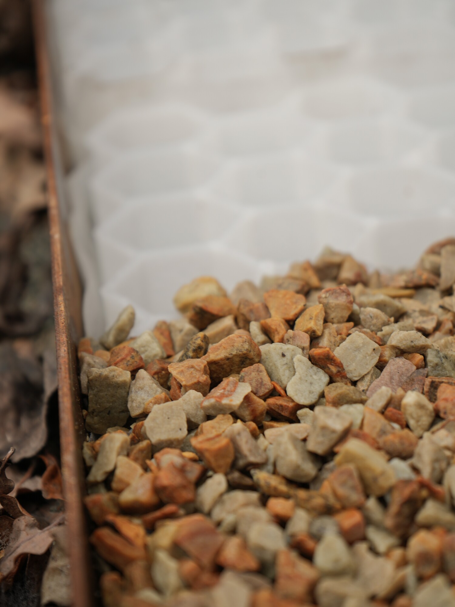 Pile of small rocks in the foreground, with a translucent honeycomb-patterned surface behind