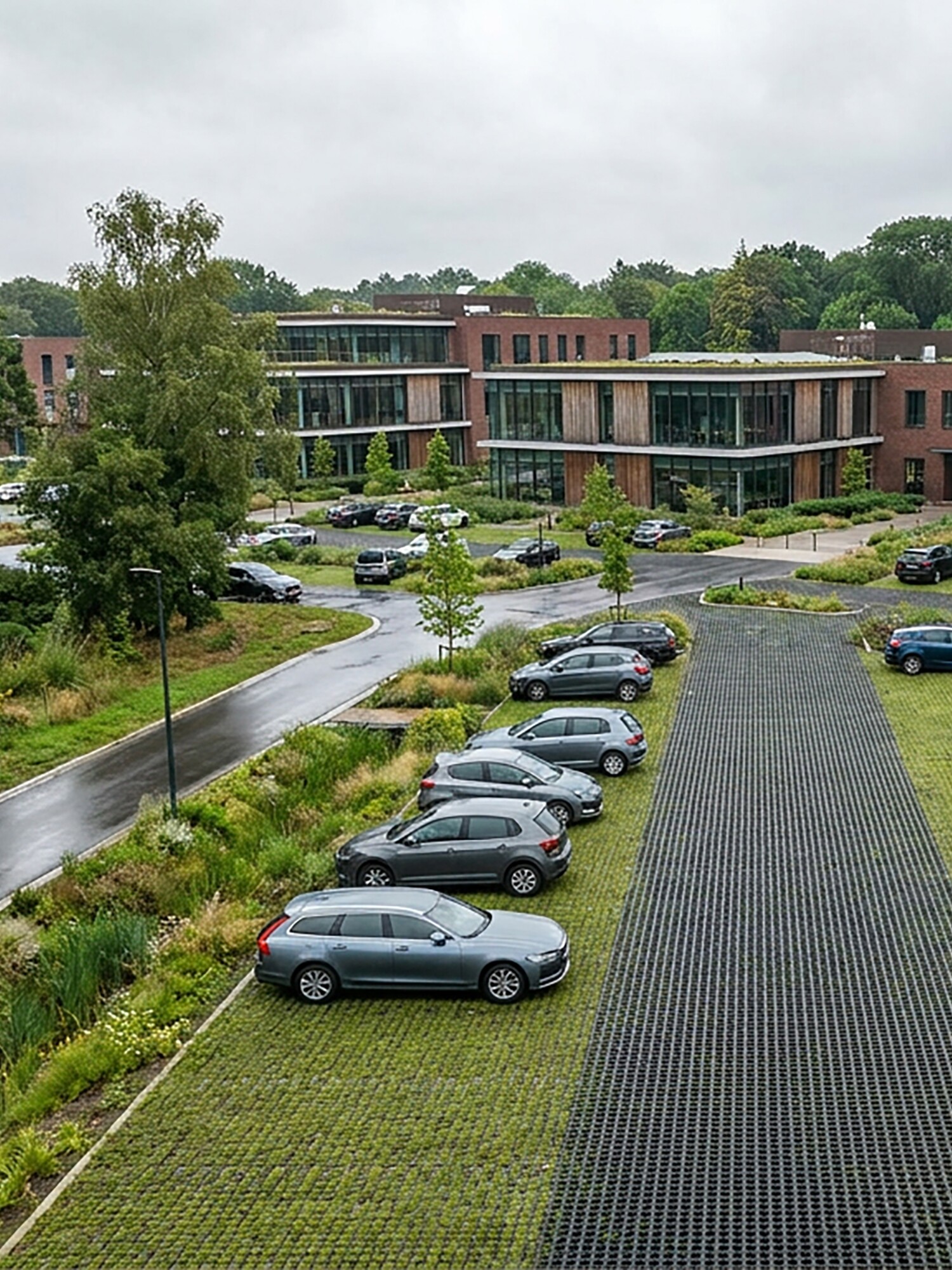 Modern brick building with parking lot and trees on a cloudy day