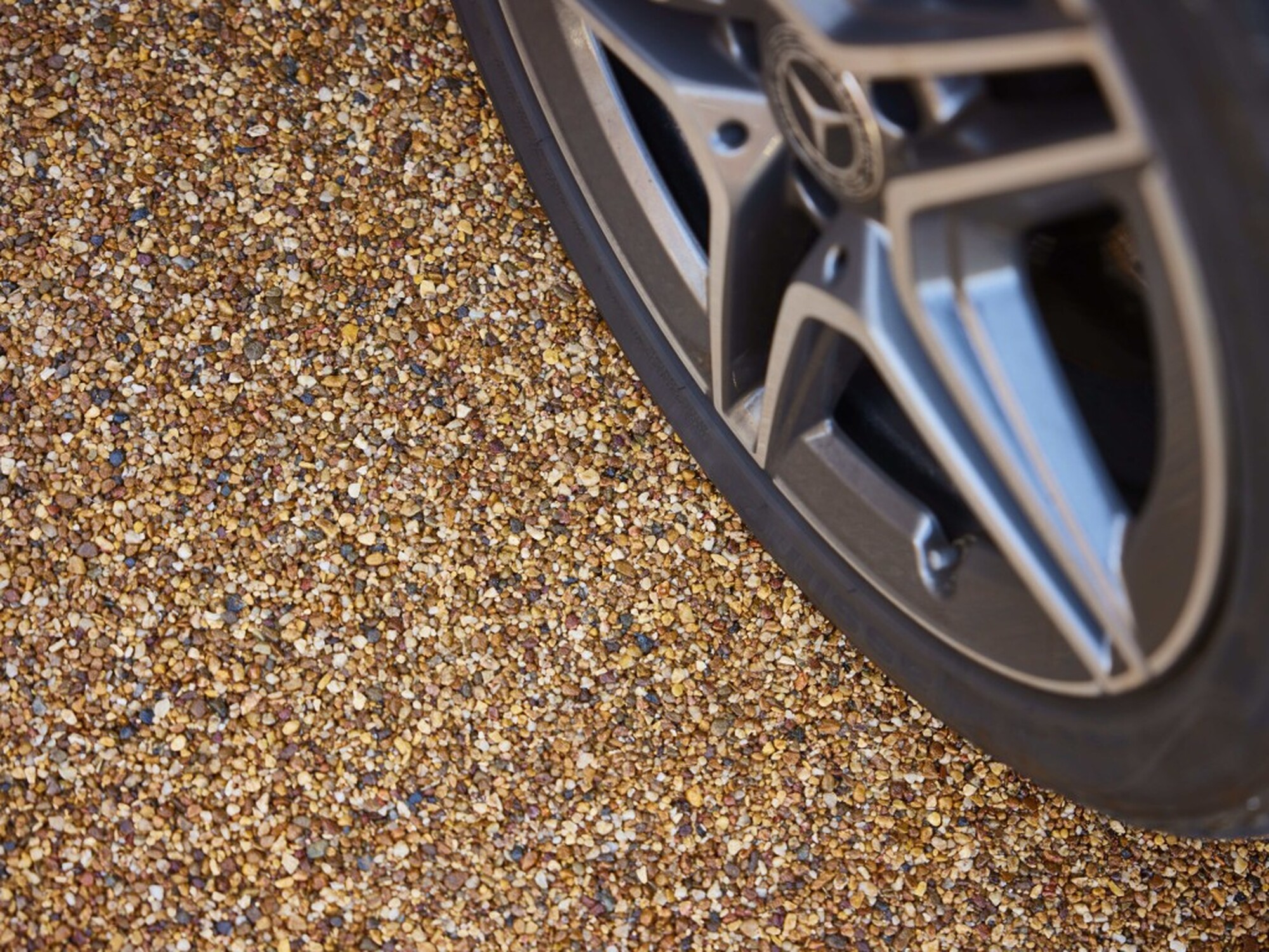Close-up of a car’s alloy wheel on gravel