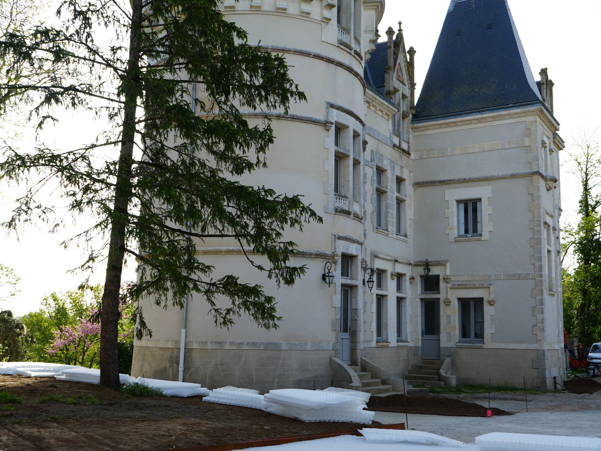Bâtiment blanc semblable à un château avec des tourelles bleues derrière une pelouse enneigée