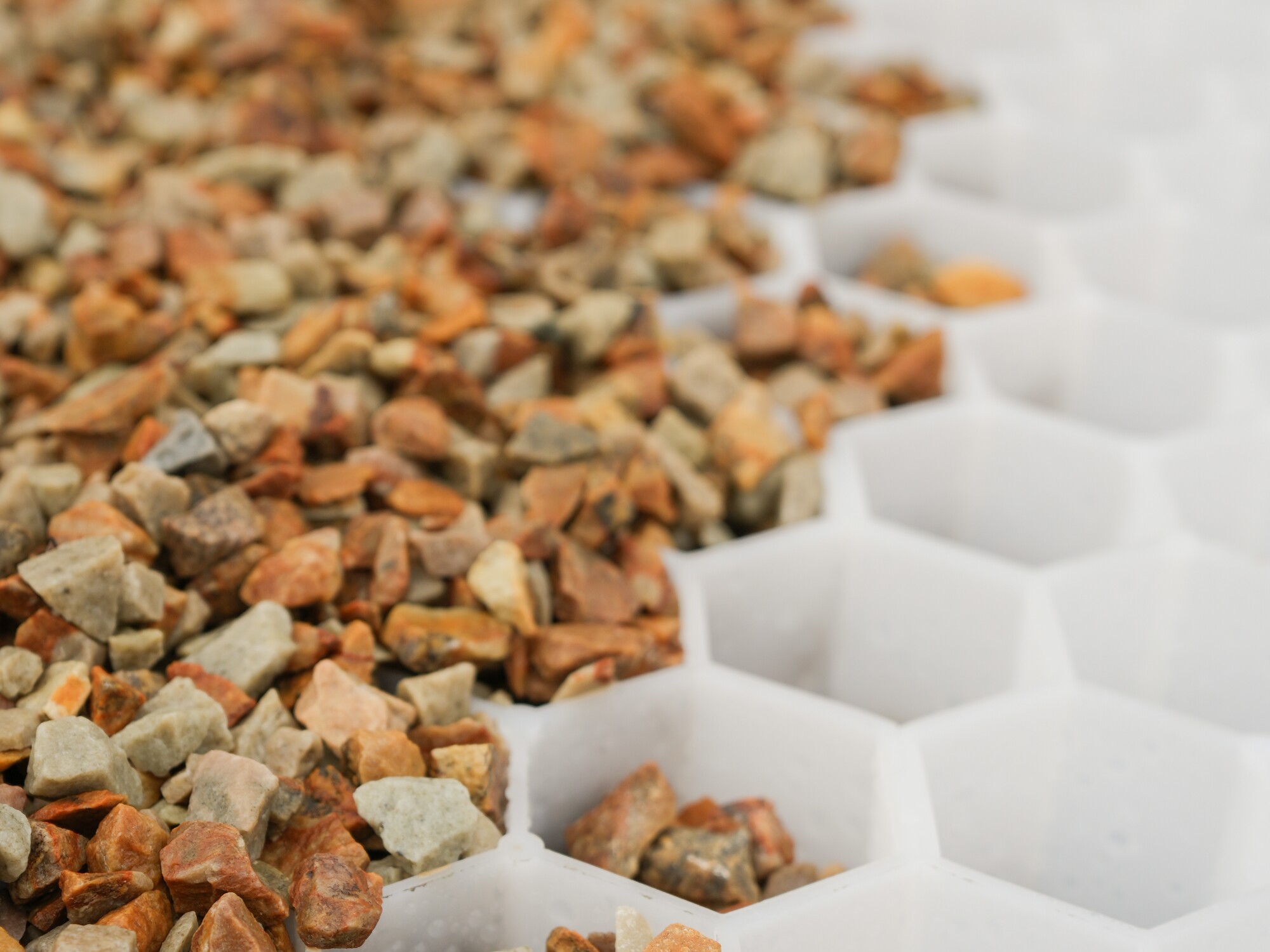 Gravel spread over a white honeycomb grid surface