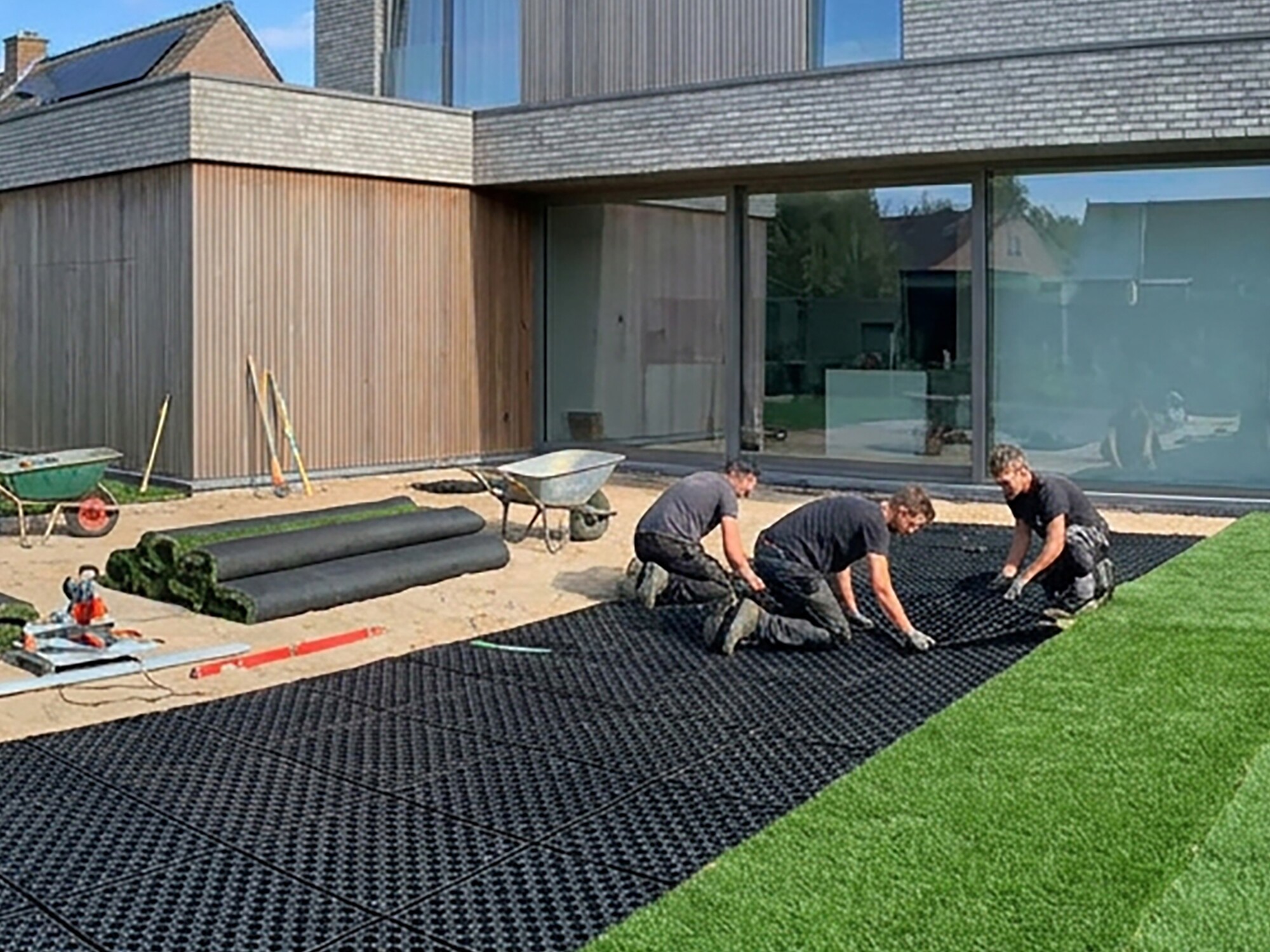 People doing floor exercises on mats beside a modern house and green lawn