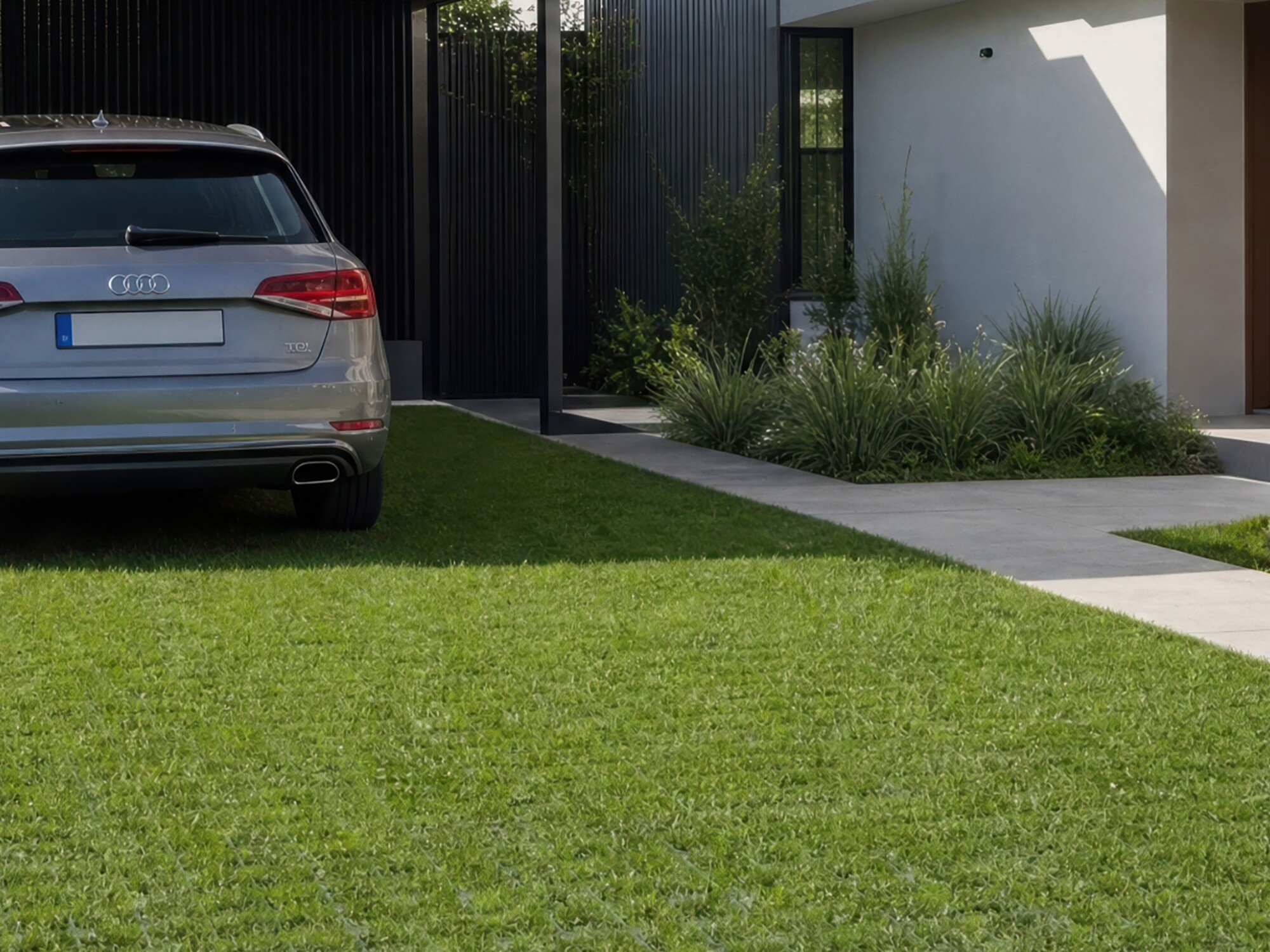 Modern house exterior with covered driveway, parked car, and green lawn