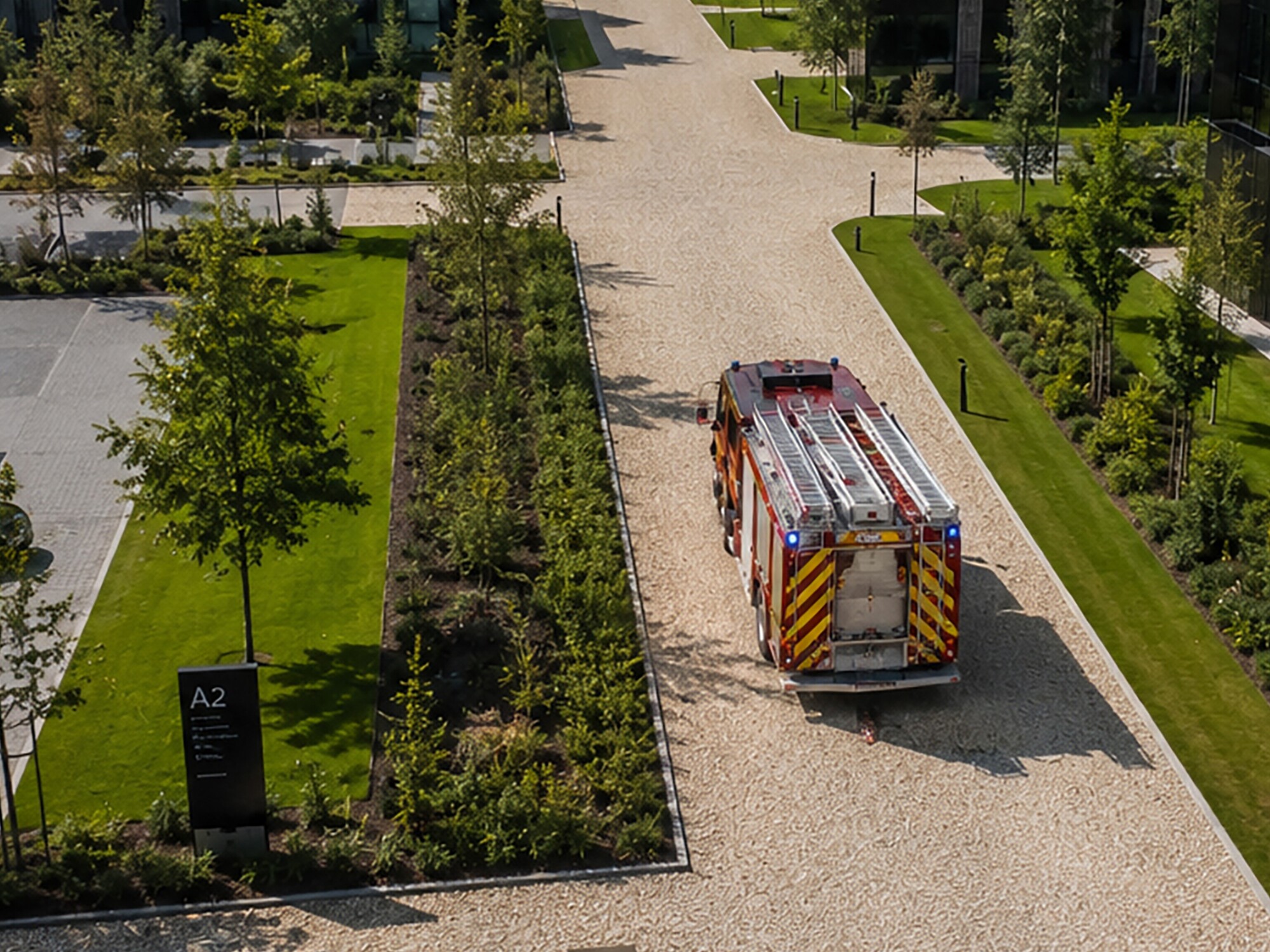 Aerial view of a campus walkway with trees and a striped barricade on the path