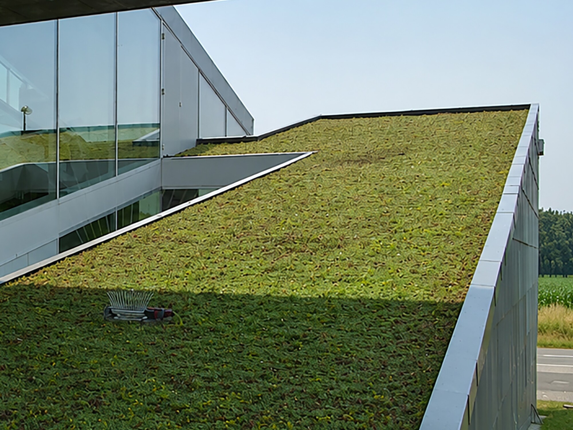 Modern building with a sloped green roof under a concrete overhang