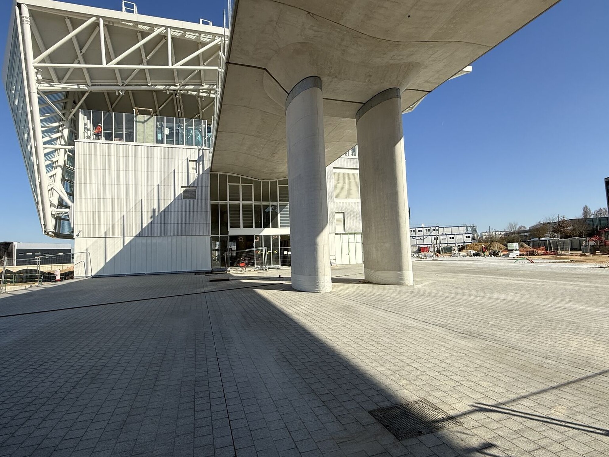 Concrete columns under an elevated structure, wide paved area in bright sunlight