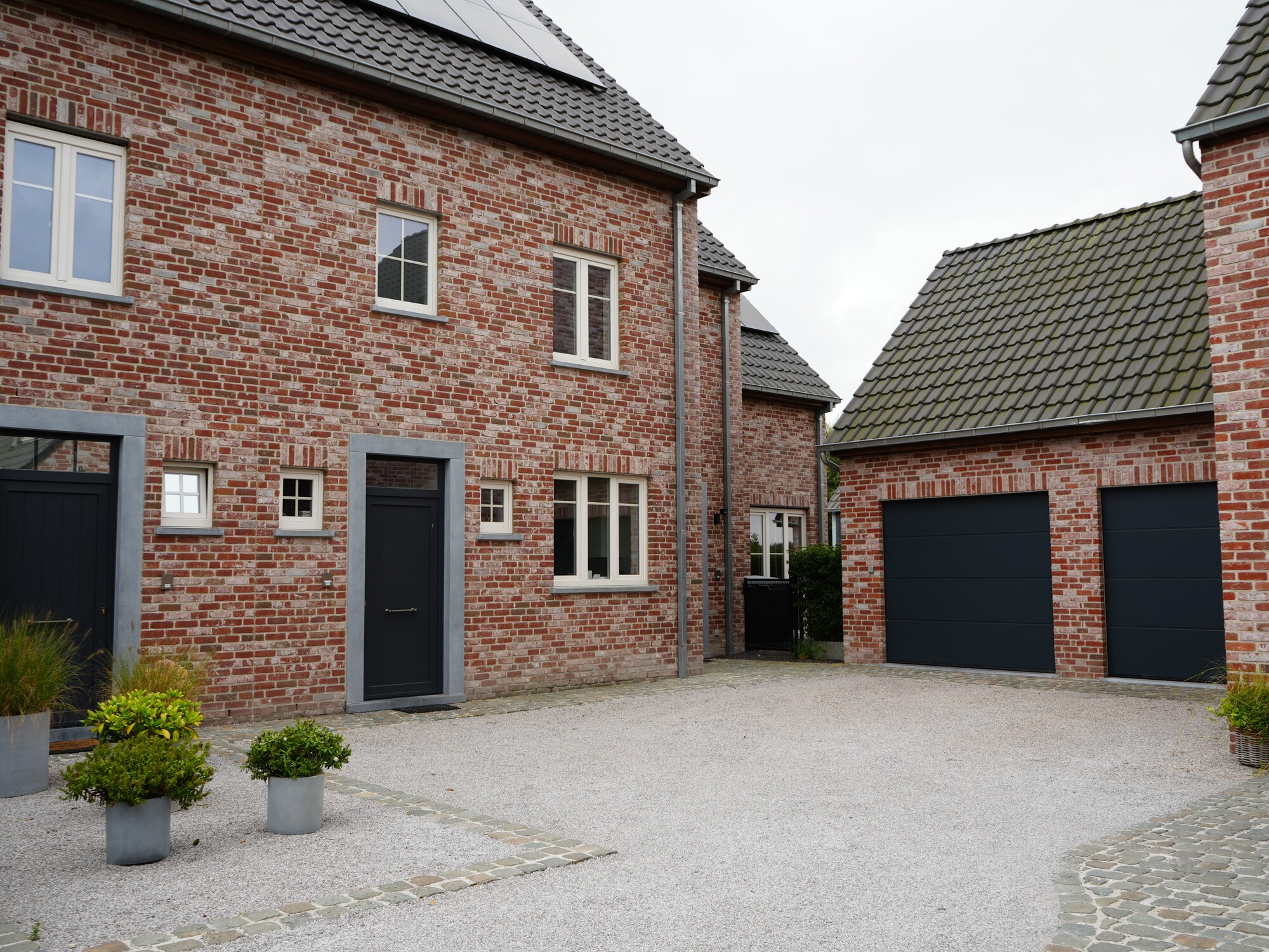 Brick houses with paved driveway and two black garage doors