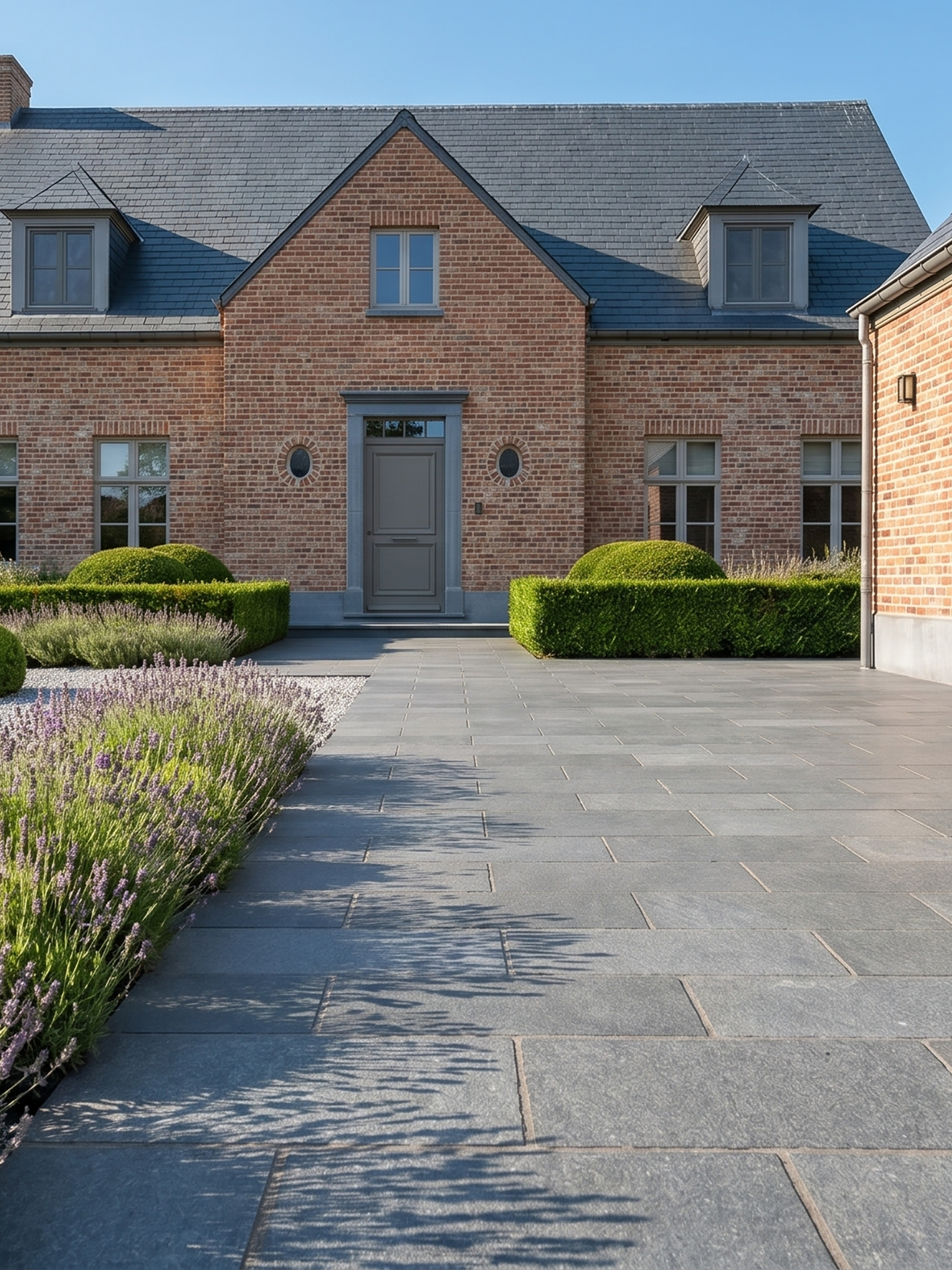 Modern brick house with dark door and slate walkway bordered by hedges