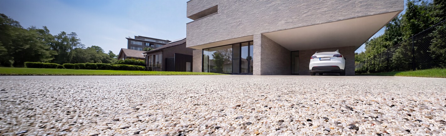 Bâtiment moderne avec passage ouvert, vu en contre-plongée au-dessus d’une cour gravillonnée